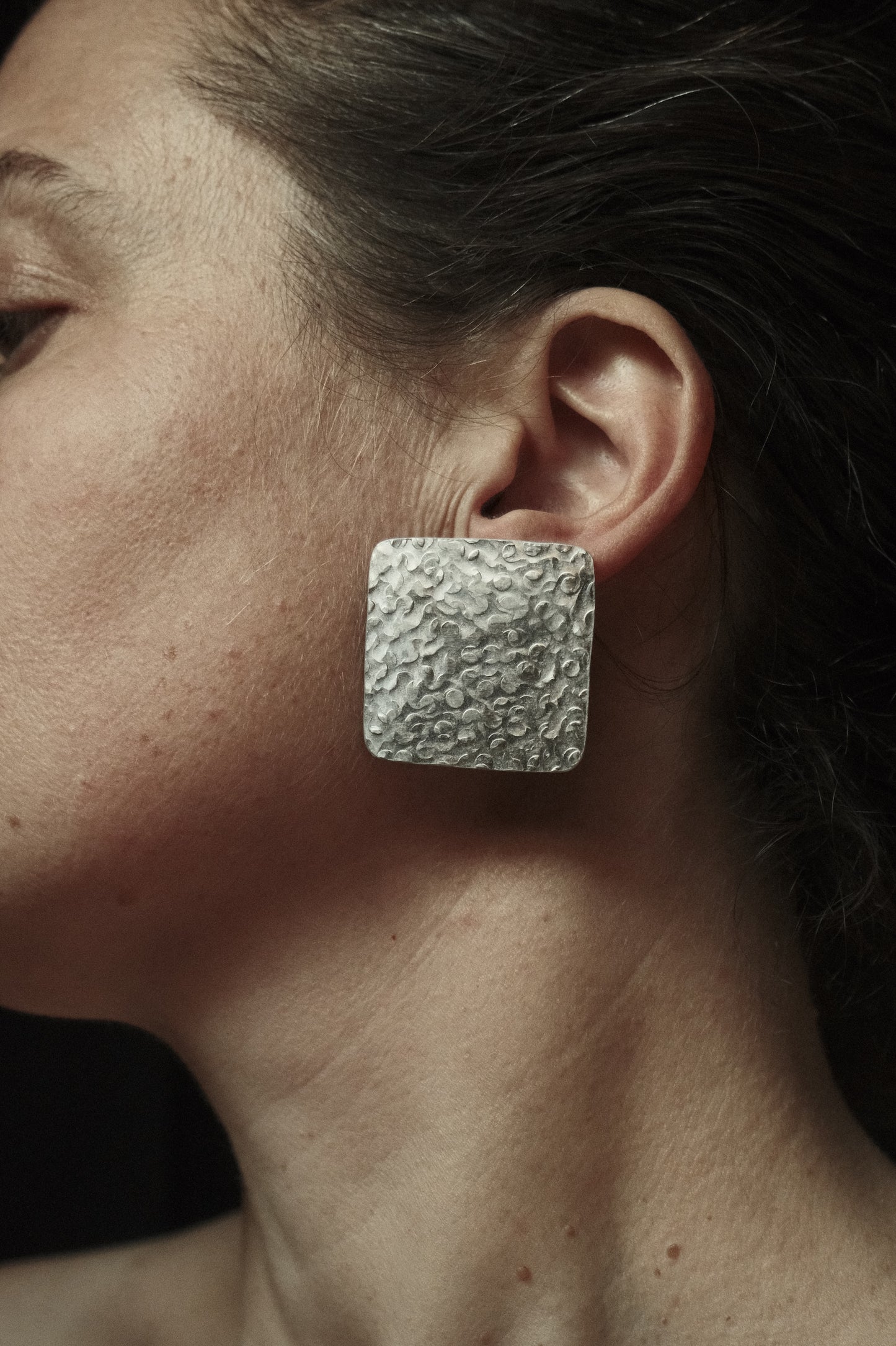 Boucles d’oreilles de forme carré, martelée donnant un aspect brut et irrégulier. Couleur argentée.