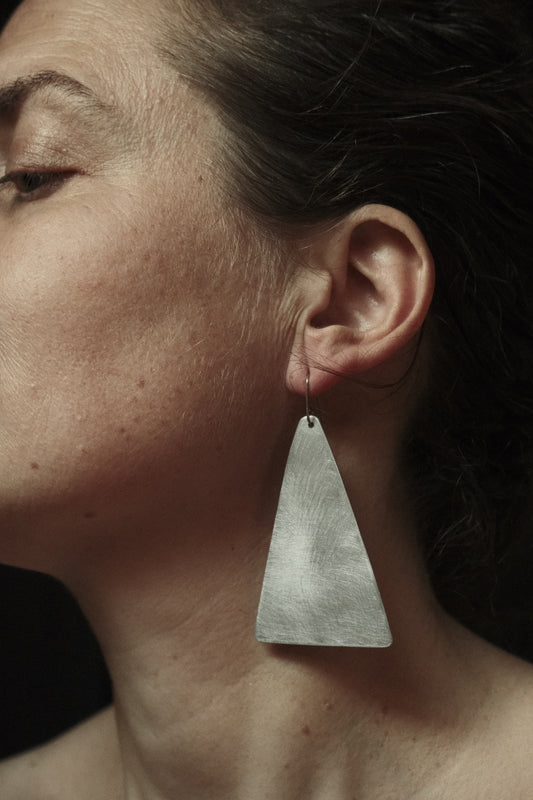 Grandes boucles d’oreilles pendantes en aluminium brossé de forme triangulaires.
